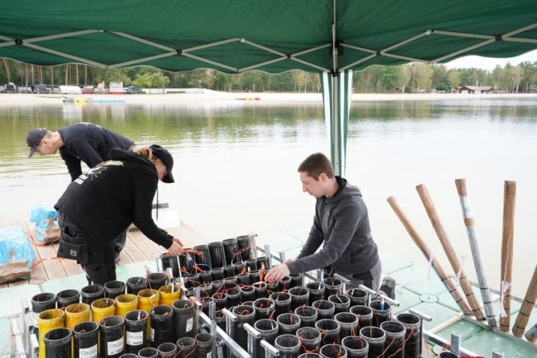 Pyrotechniker beladen die Abschussvorrichtungen mit Pyrotechnik am Tankumsee