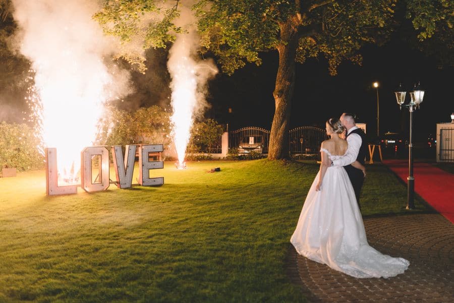 ein hochzeitspaar vor einem love feuerwerk