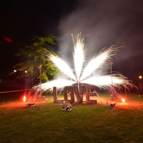 Ein Feuerwerksfächer vor einem LOVE Schriftzug